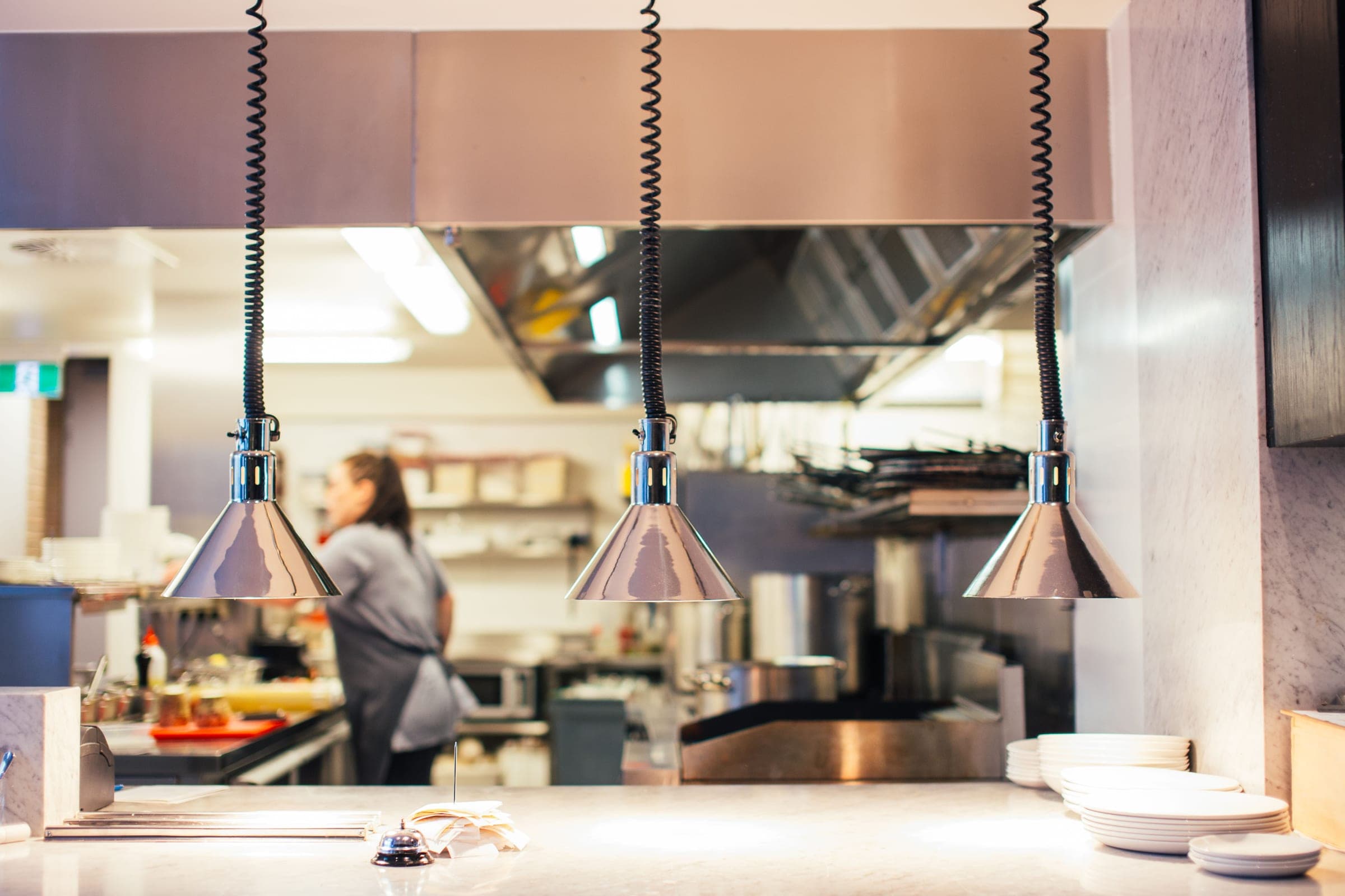 Chef working under heat lamps in a commercial kitchen